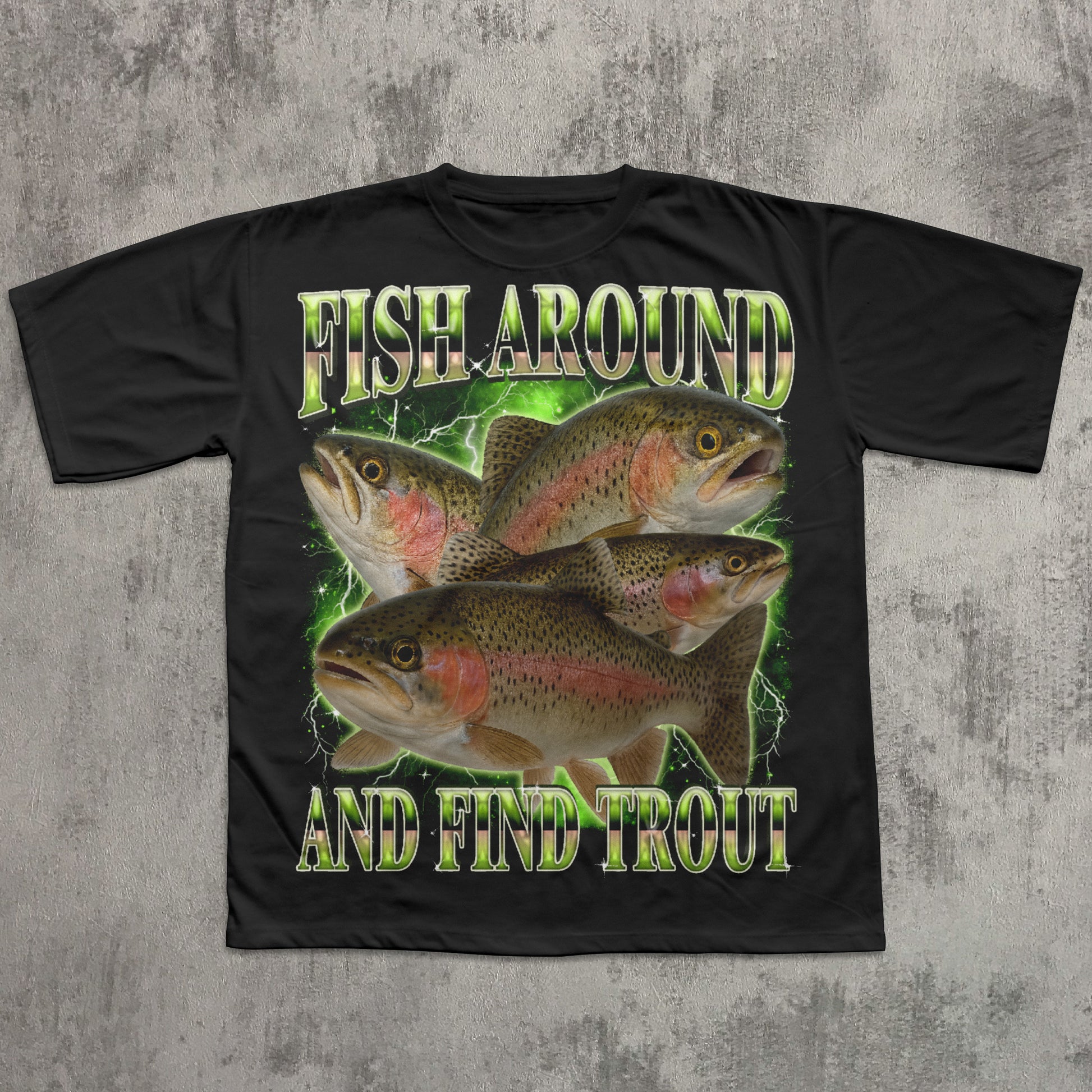 Black t-shirt with fish graphic and text 'Fish Around and Find Trout' on a textured gray background