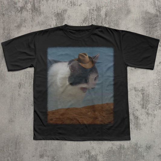 Black t-shirt with a cat wearing a cowboy hat graphic on a textured gray background