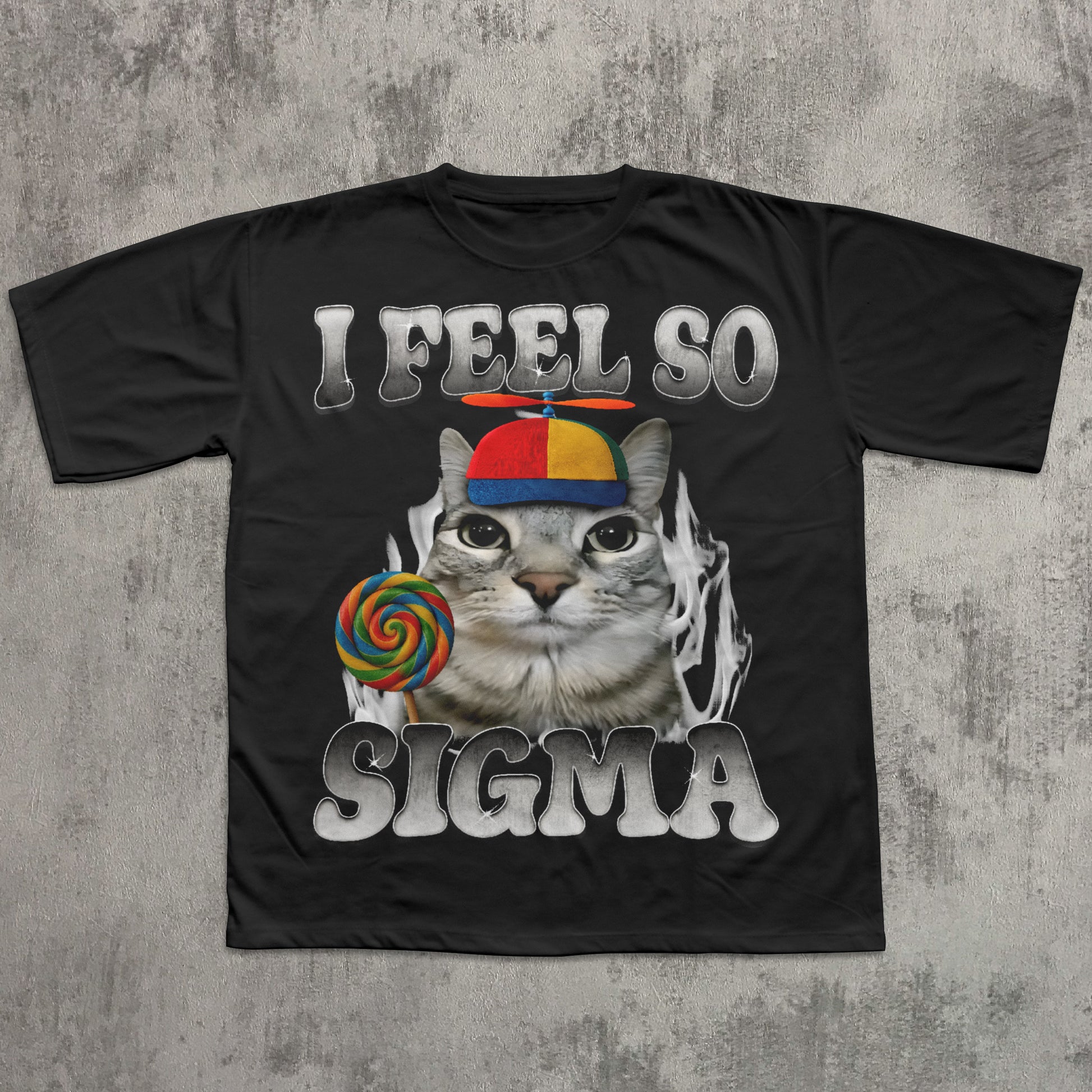 Black t-shirt with a cat graphic and text 'I Feel So Sigma' on a textured gray background