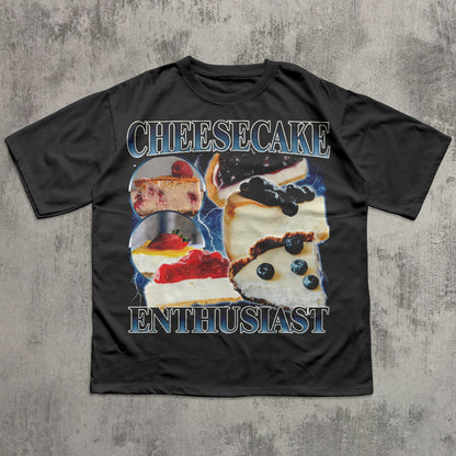 Black t-shirt with cheesecake graphic and text on a textured gray background