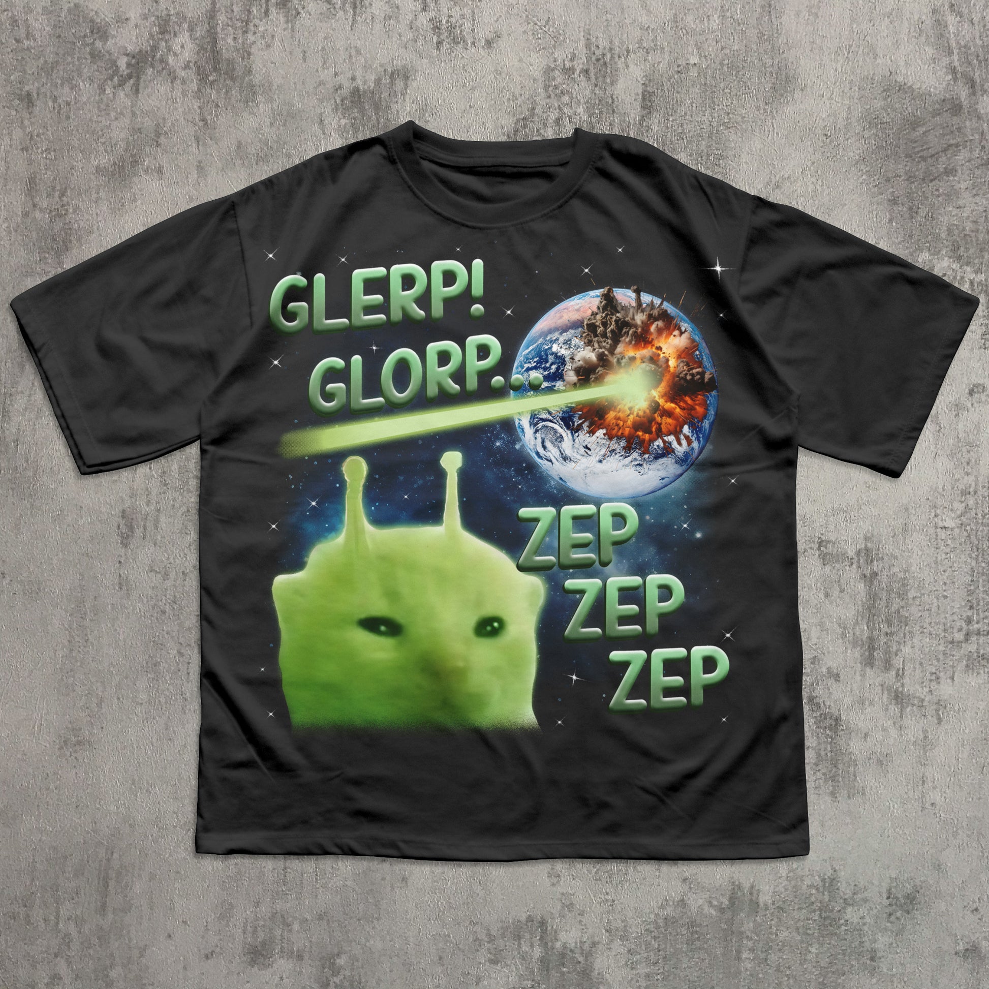Black t-shirt with a green alien and space-themed design on a concrete surface