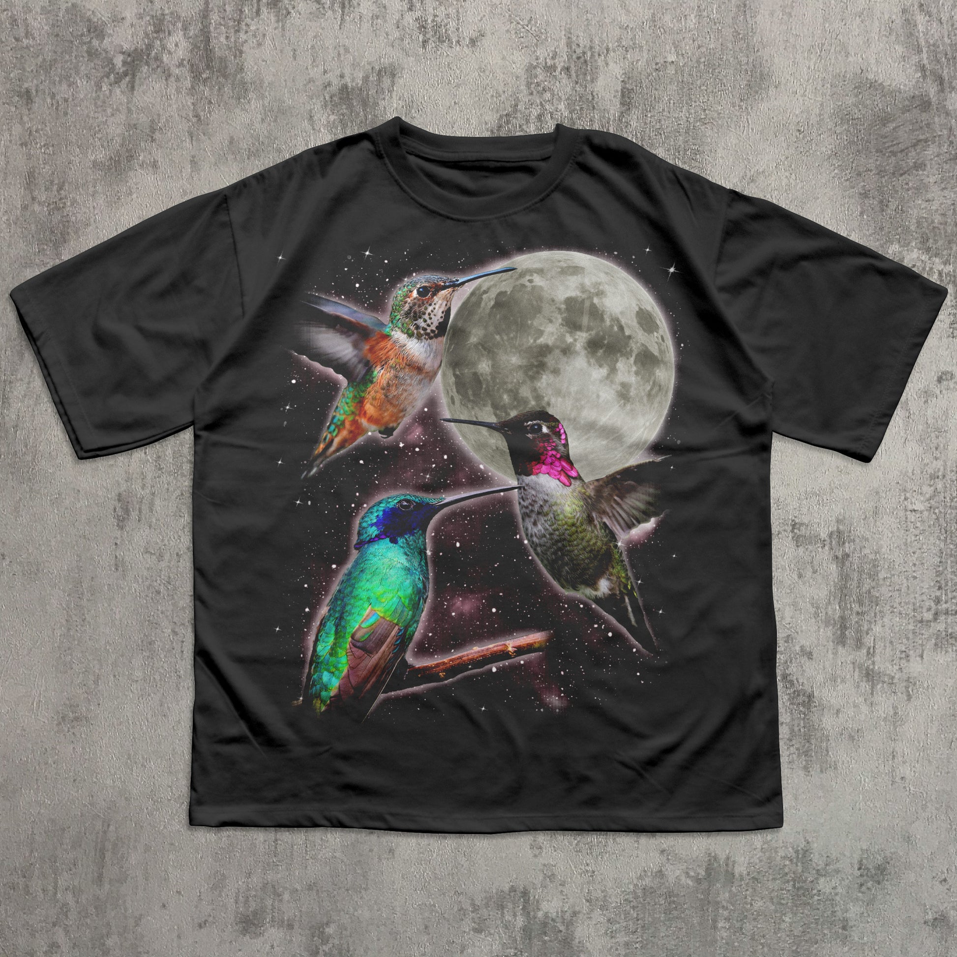 Black t-shirt with colorful hummingbird design and moon on a textured gray background