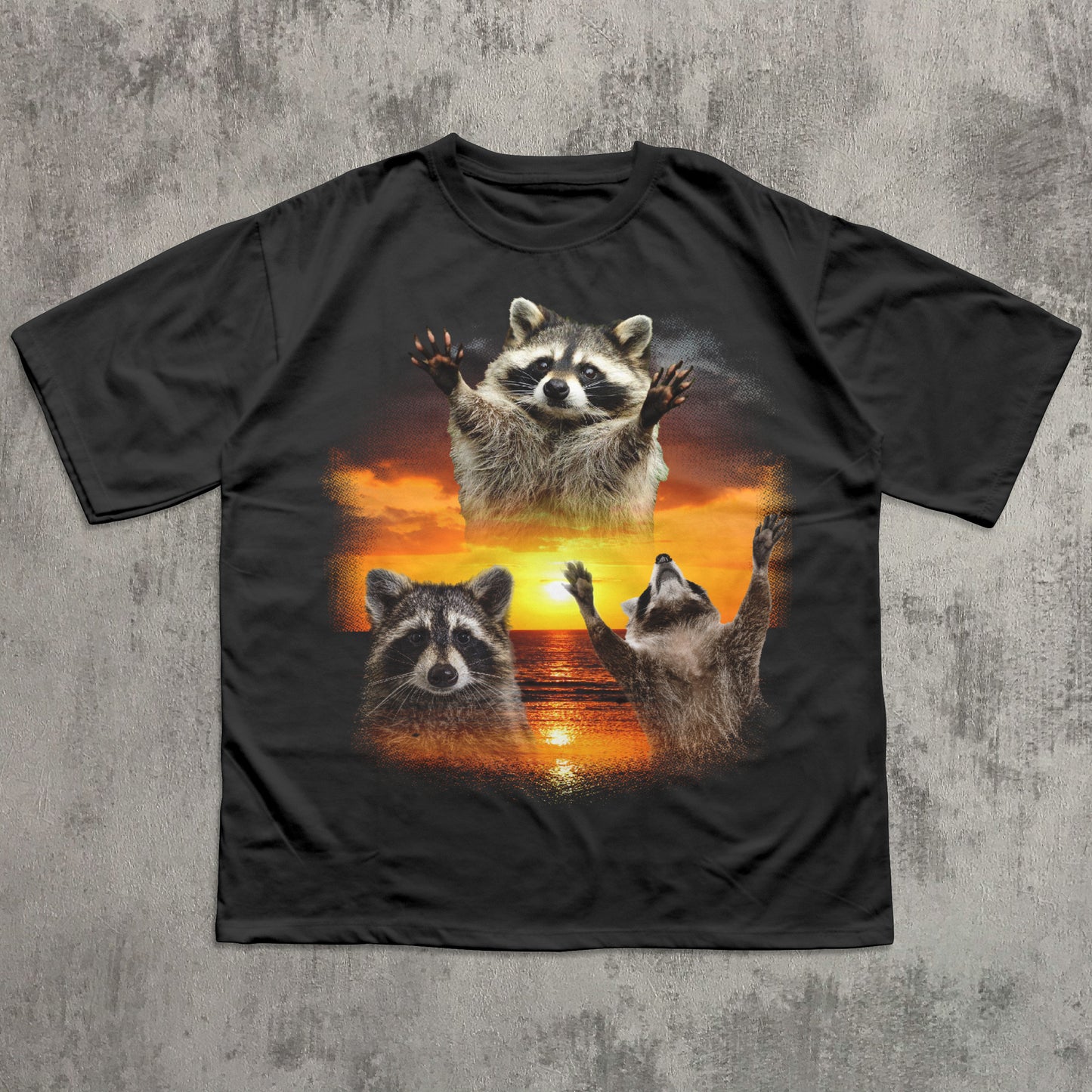 Black t-shirt with raccoon design on a textured gray background
