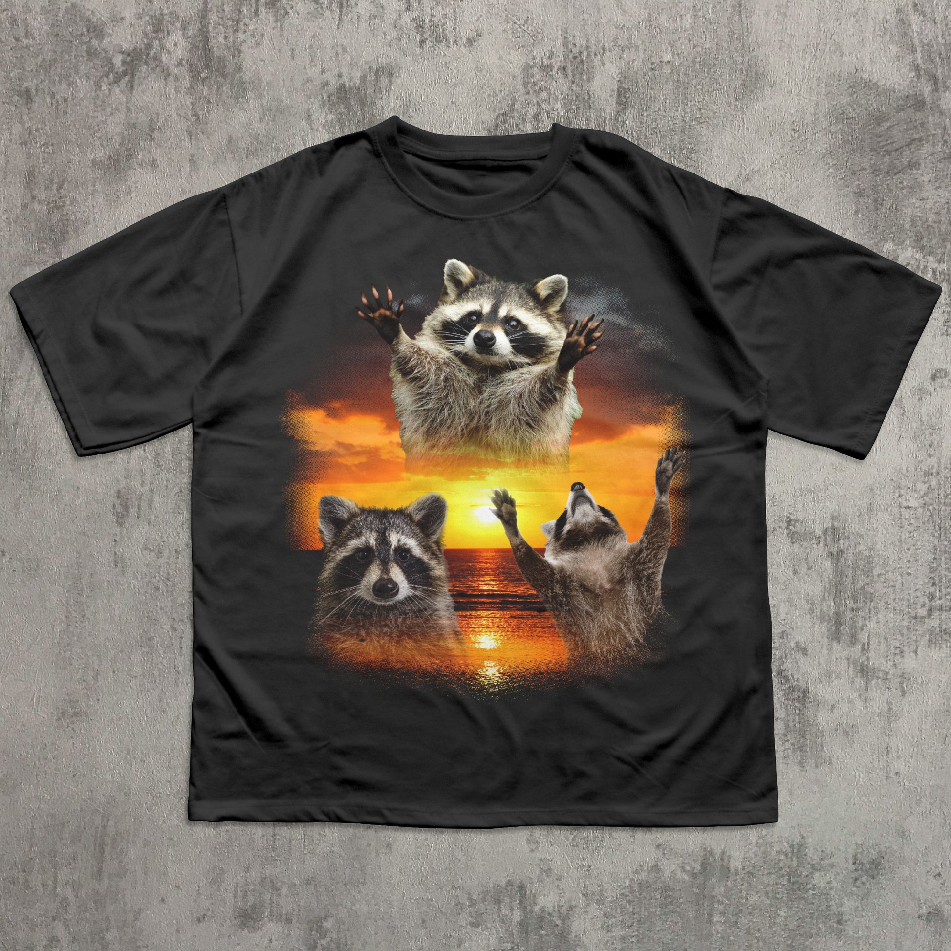 Black t-shirt with raccoon design on a textured gray background