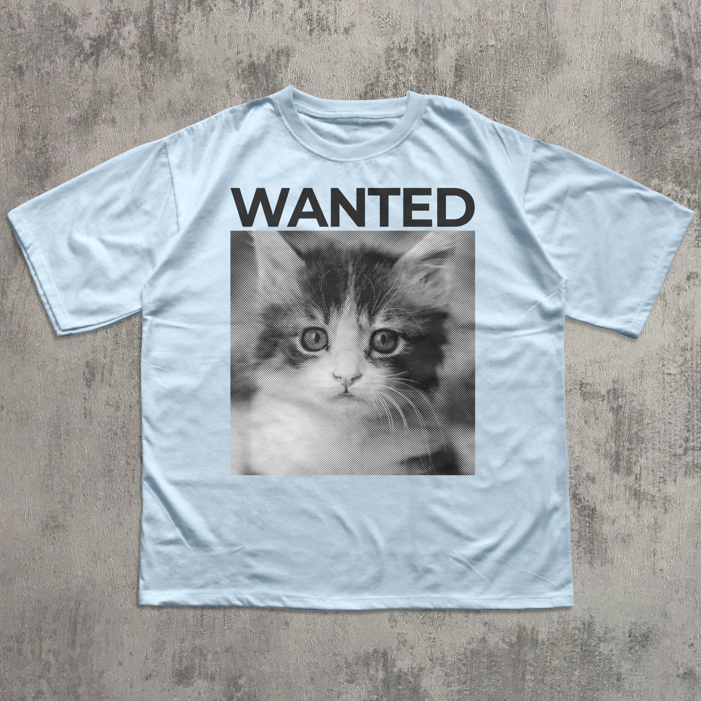 Light blue t-shirt with a kitten photo and 'WANTED' text on a textured surface