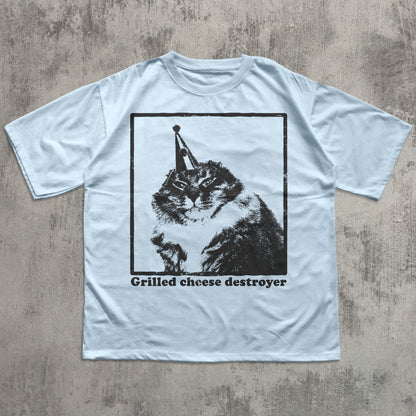 Light blue t-shirt with a graphic of a cat and text 'Grilled cheese destroyer' on a textured surface.