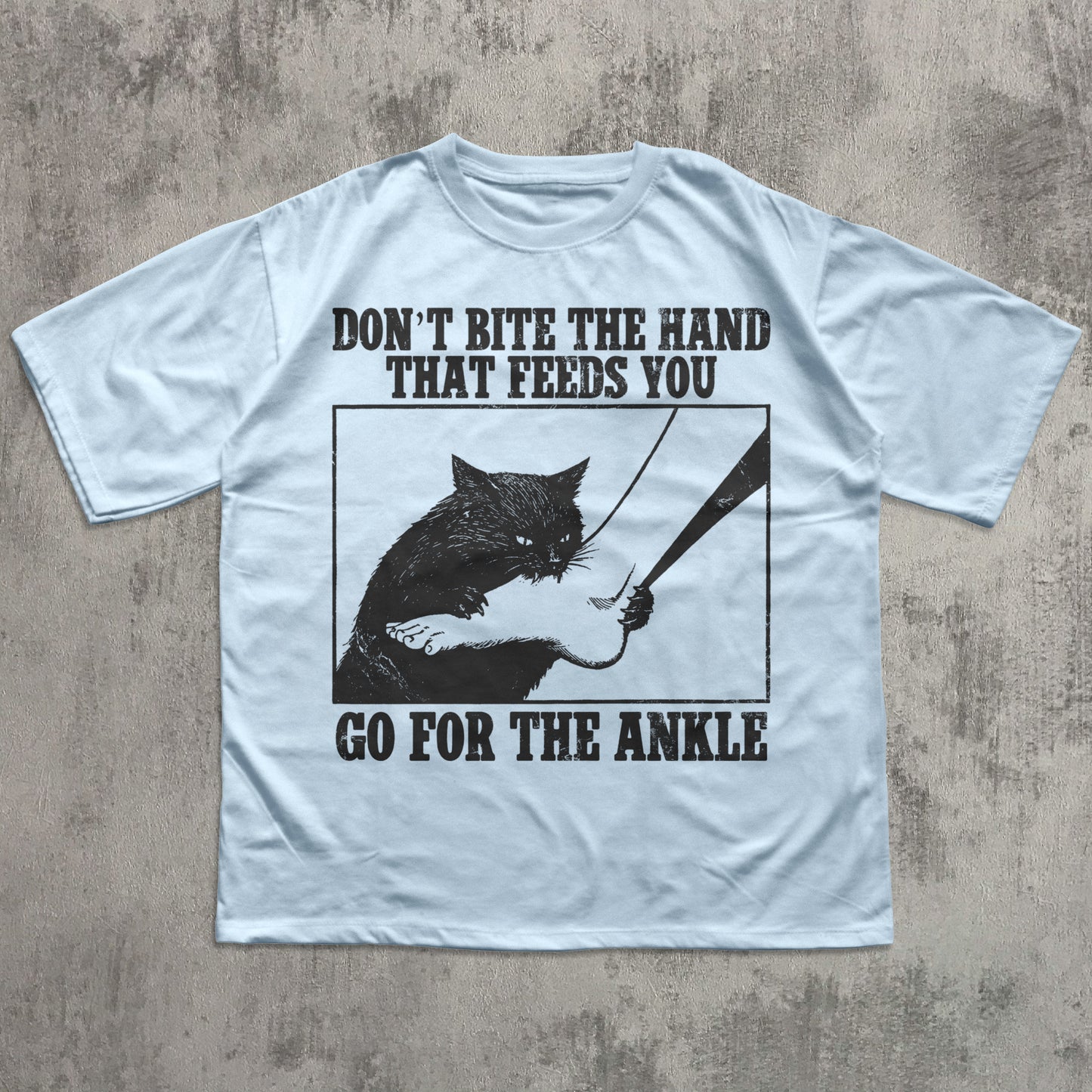 Light blue t-shirt with graphic design and text on a textured surface