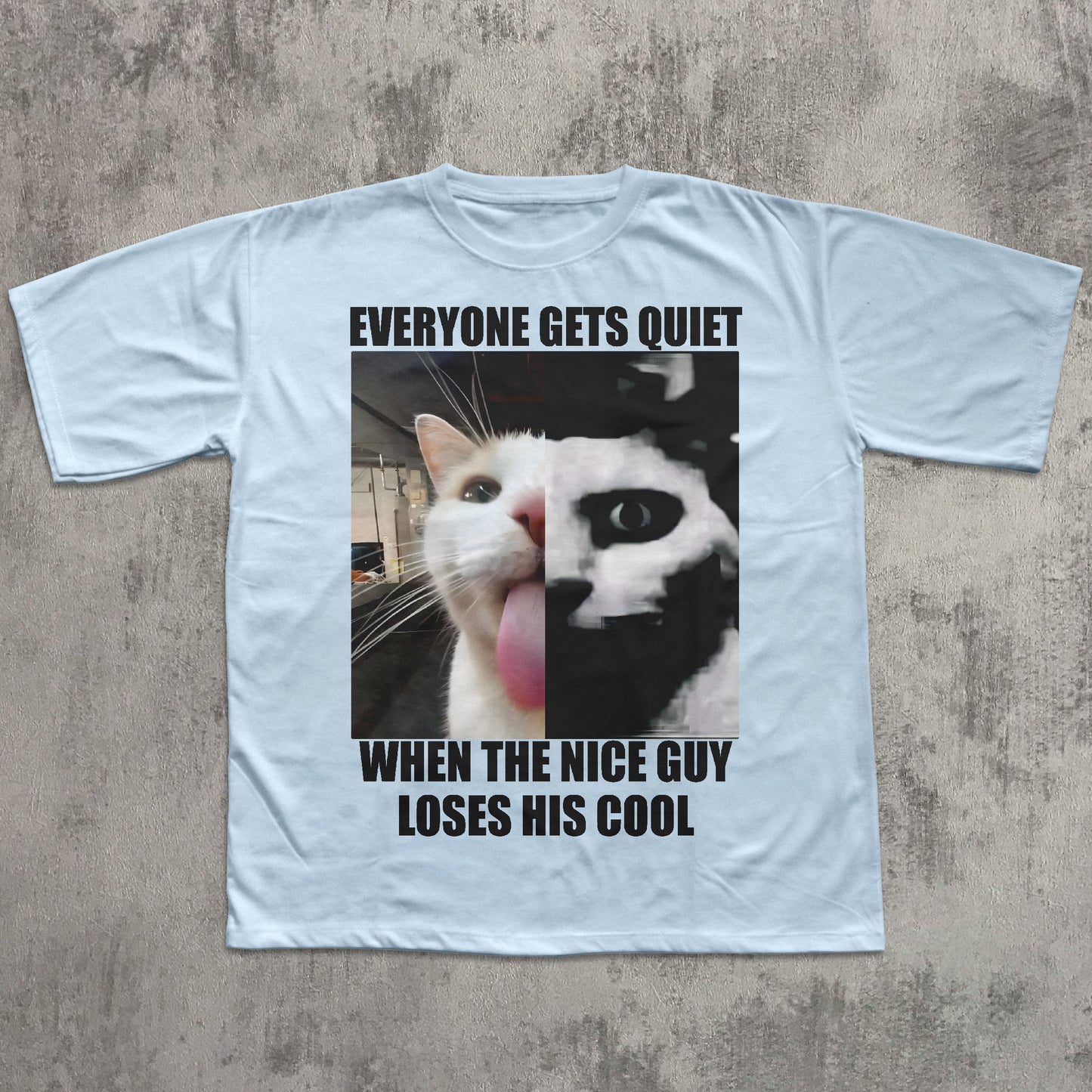 Light blue t-shirt with a graphic of a cat and text on a concrete surface