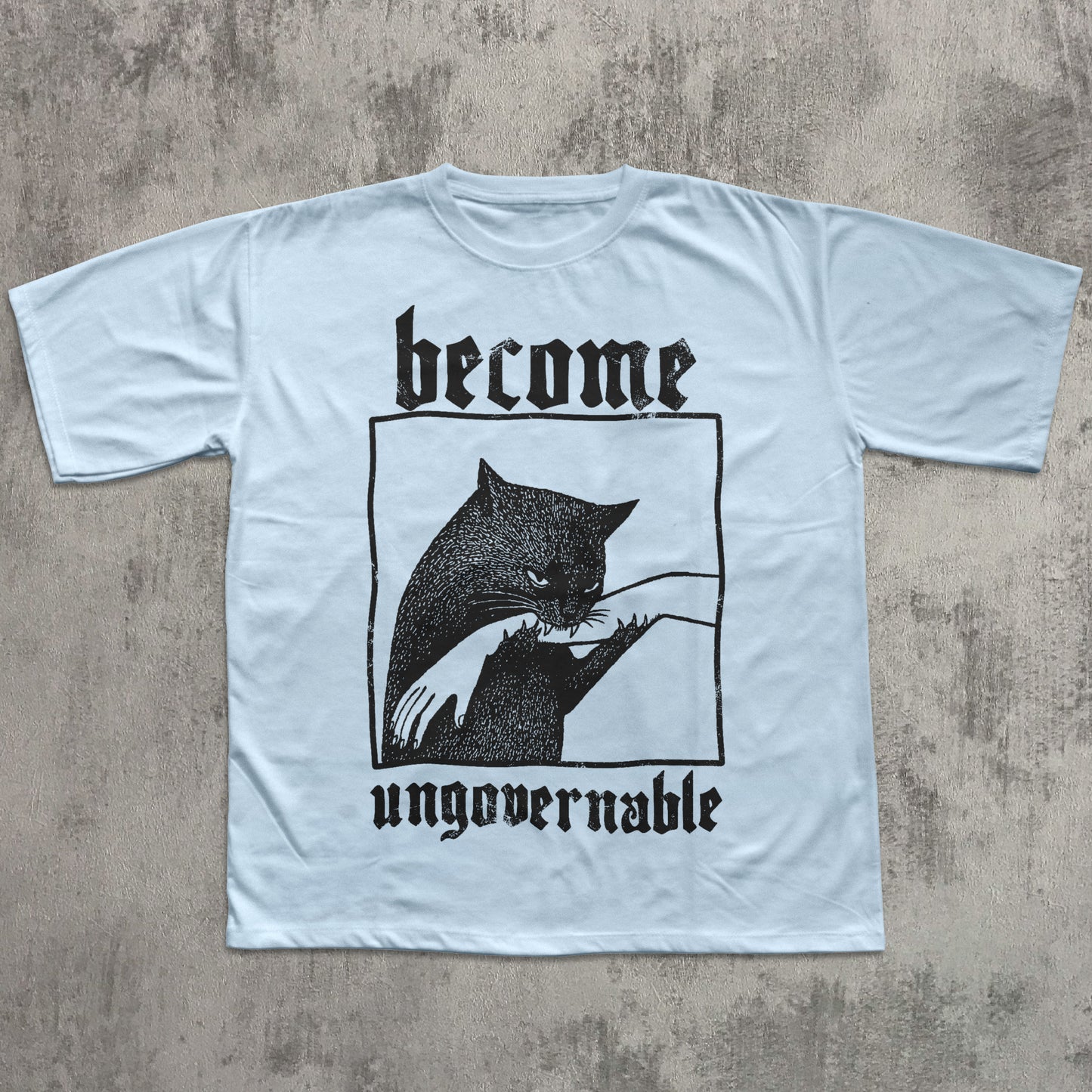 Light blue t-shirt with black graphic and text 'become ungovernable' on a textured gray background