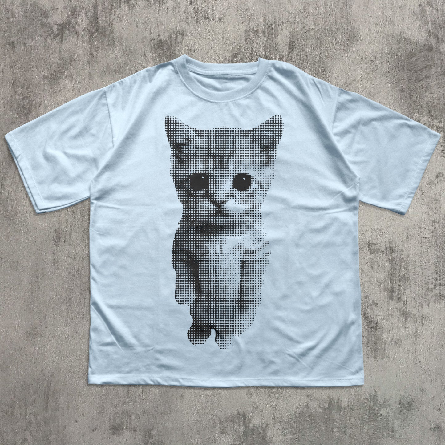 Light blue t-shirt with a printed cat design on a textured gray background