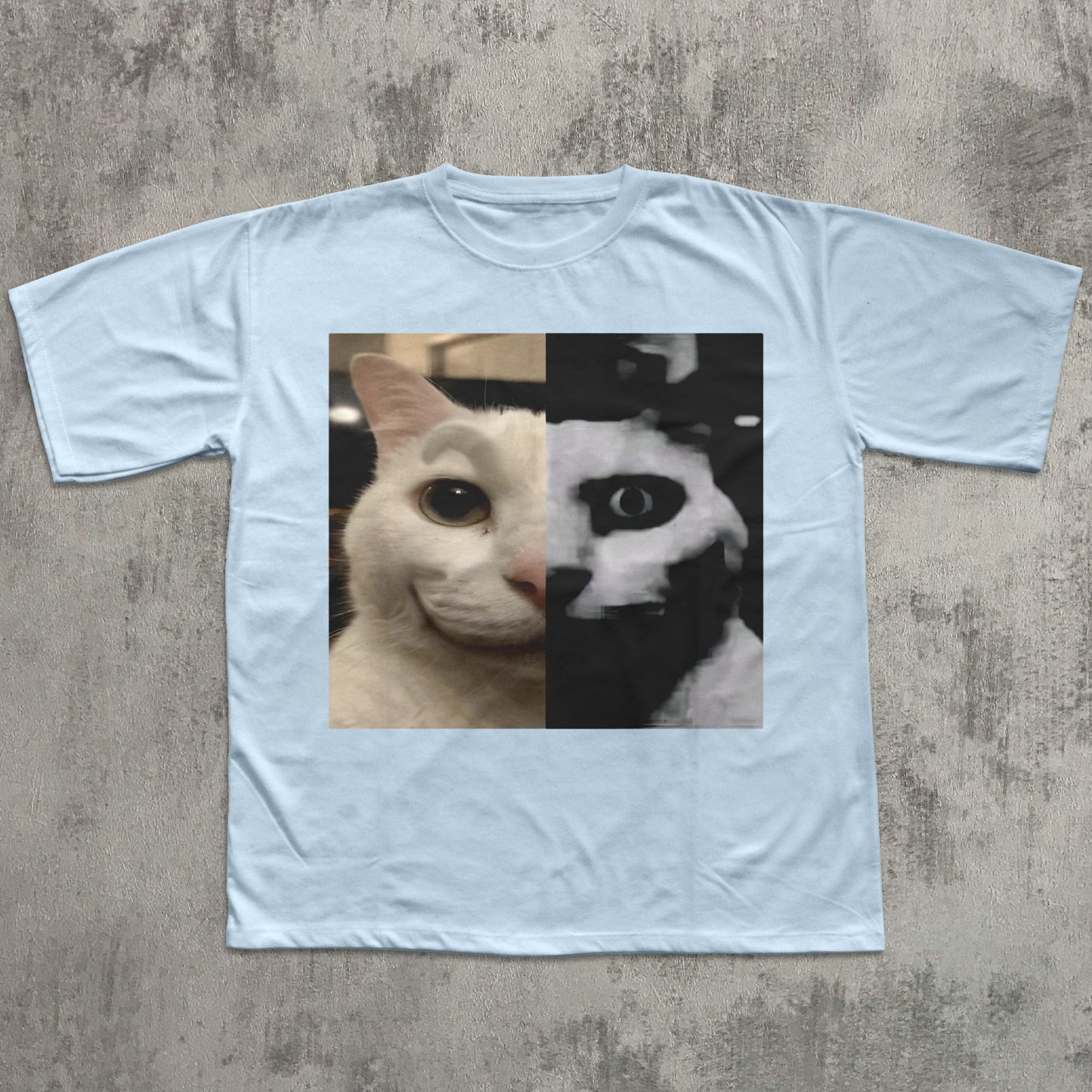 Light blue t-shirt with a cat graphic on a textured gray surface