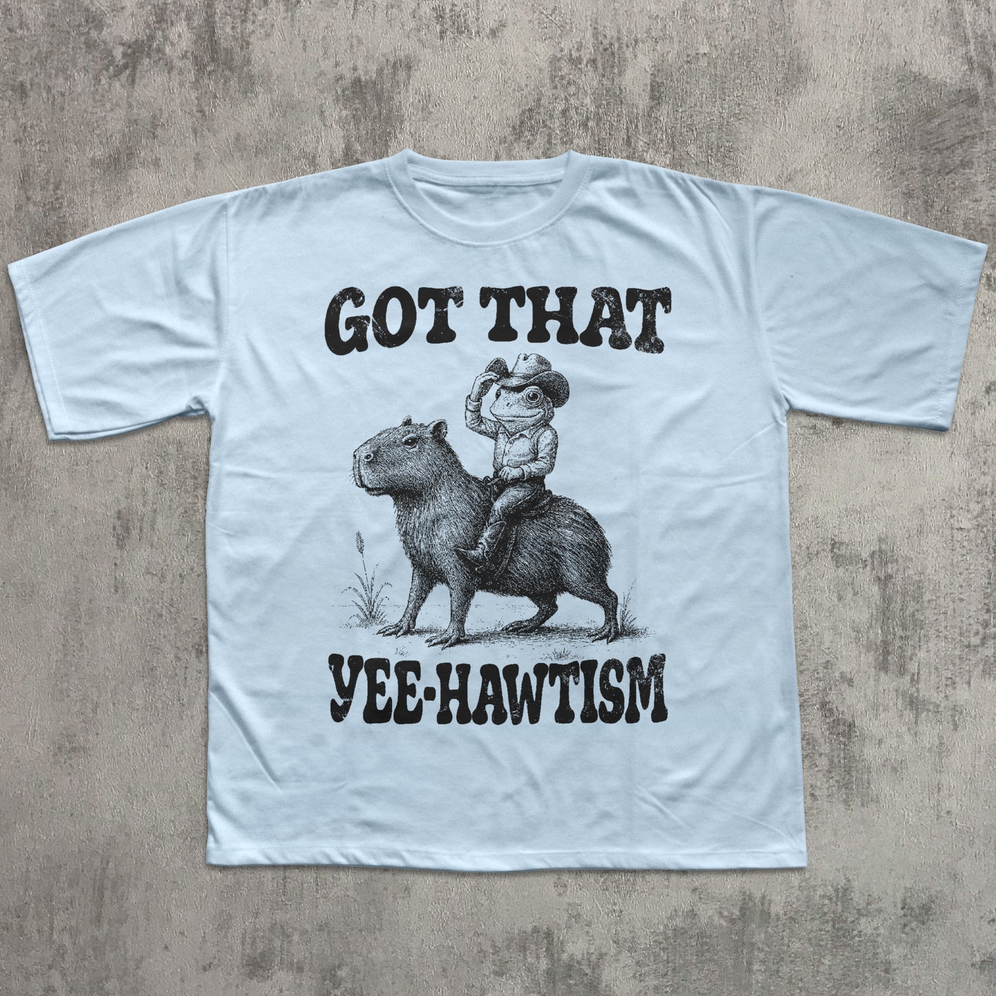 Light blue t-shirt with a graphic of a cowboy riding a horse and text on a concrete surface