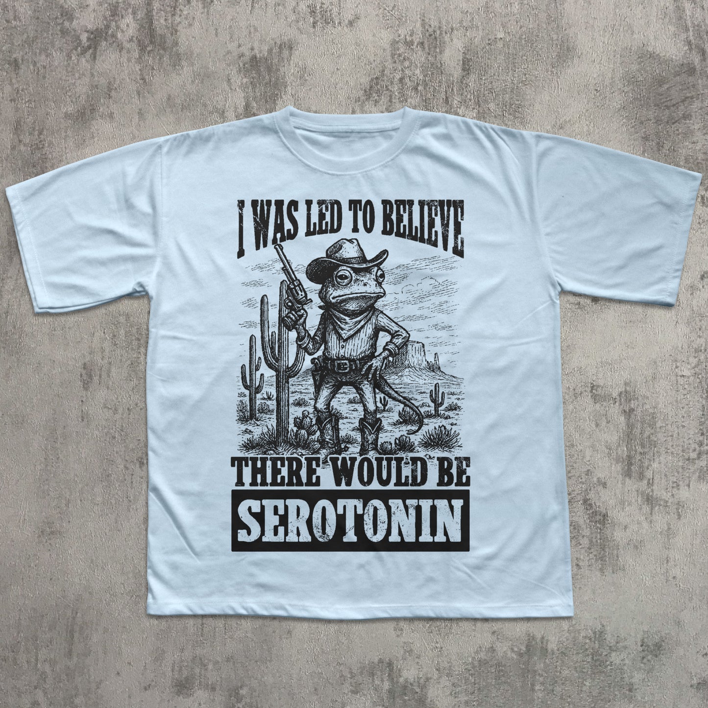 Light blue t-shirt with a graphic design and text on a concrete surface