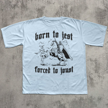 Light blue t-shirt with black graphic and text 'born to jest, forced to joust' on a textured gray background
