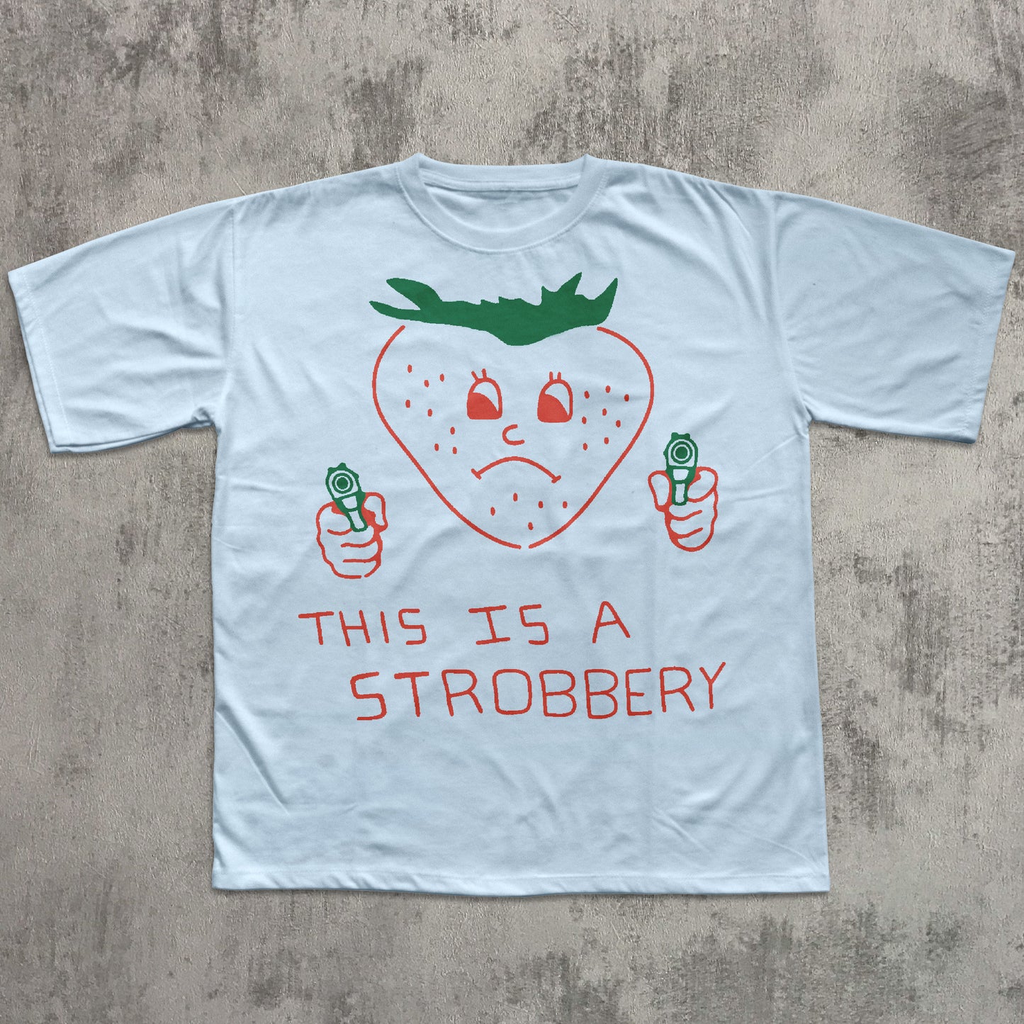 Light blue t-shirt with a strawberry graphic and text on a concrete surface