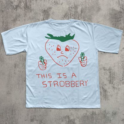Light blue t-shirt with a strawberry graphic and text on a concrete surface