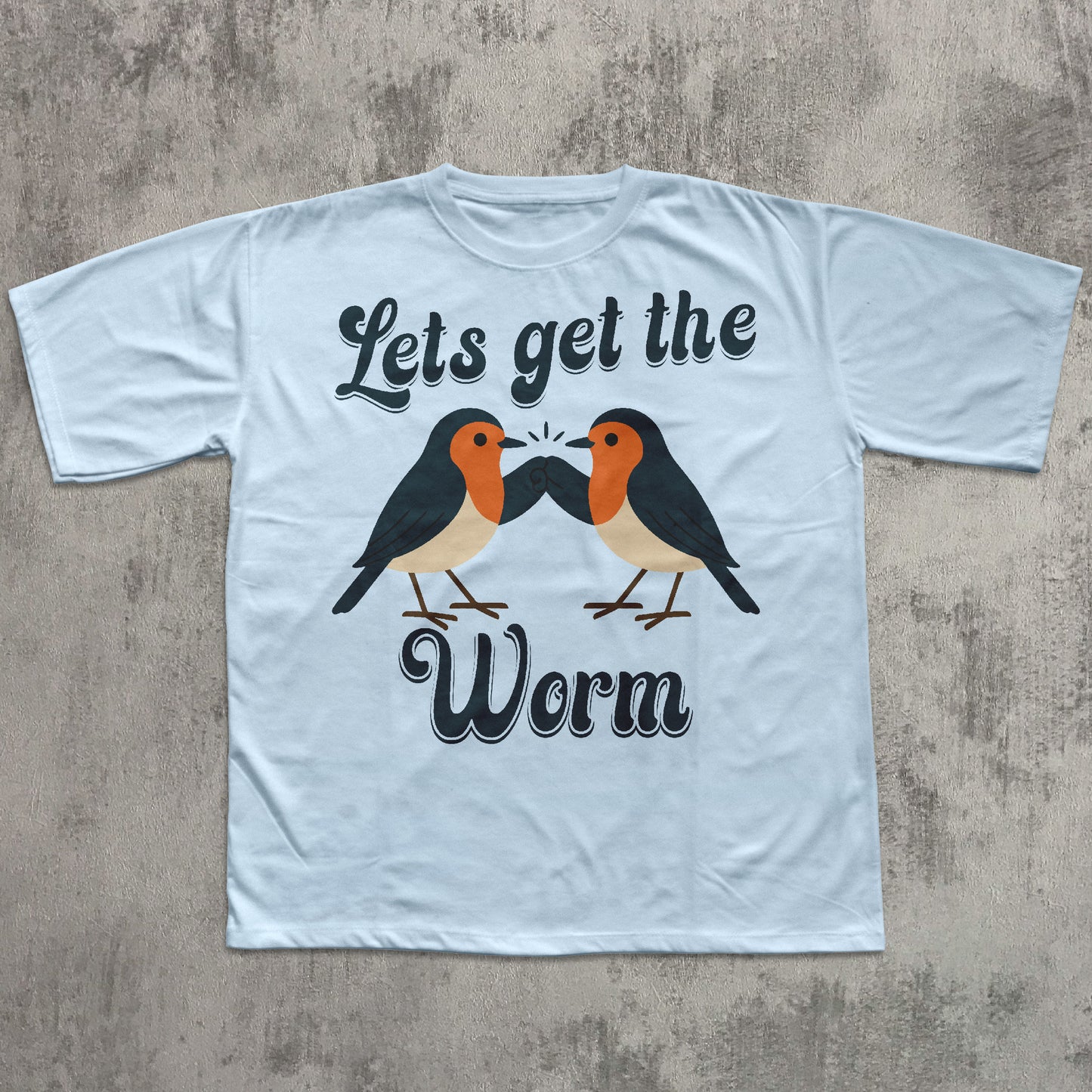 Light blue t-shirt with two birds and text 'Let's get the Worm' on a concrete surface