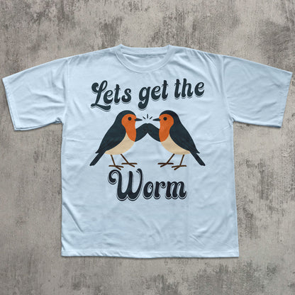 Light blue t-shirt with two birds and text 'Let's get the Worm' on a concrete surface