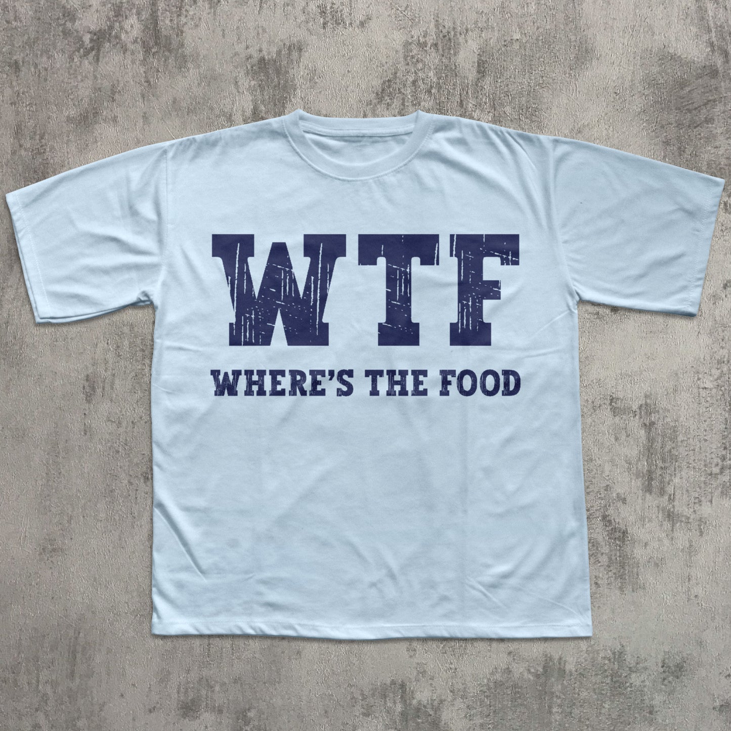 Light blue t-shirt with 'WTF WHERE'S THE FOOD' text on a concrete surface