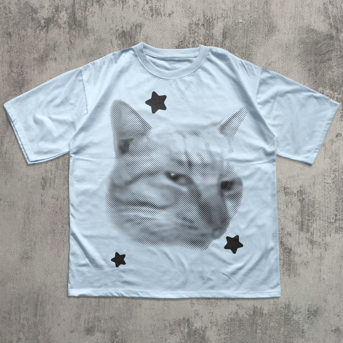 White t-shirt with a cat graphic and star shapes on a textured surface