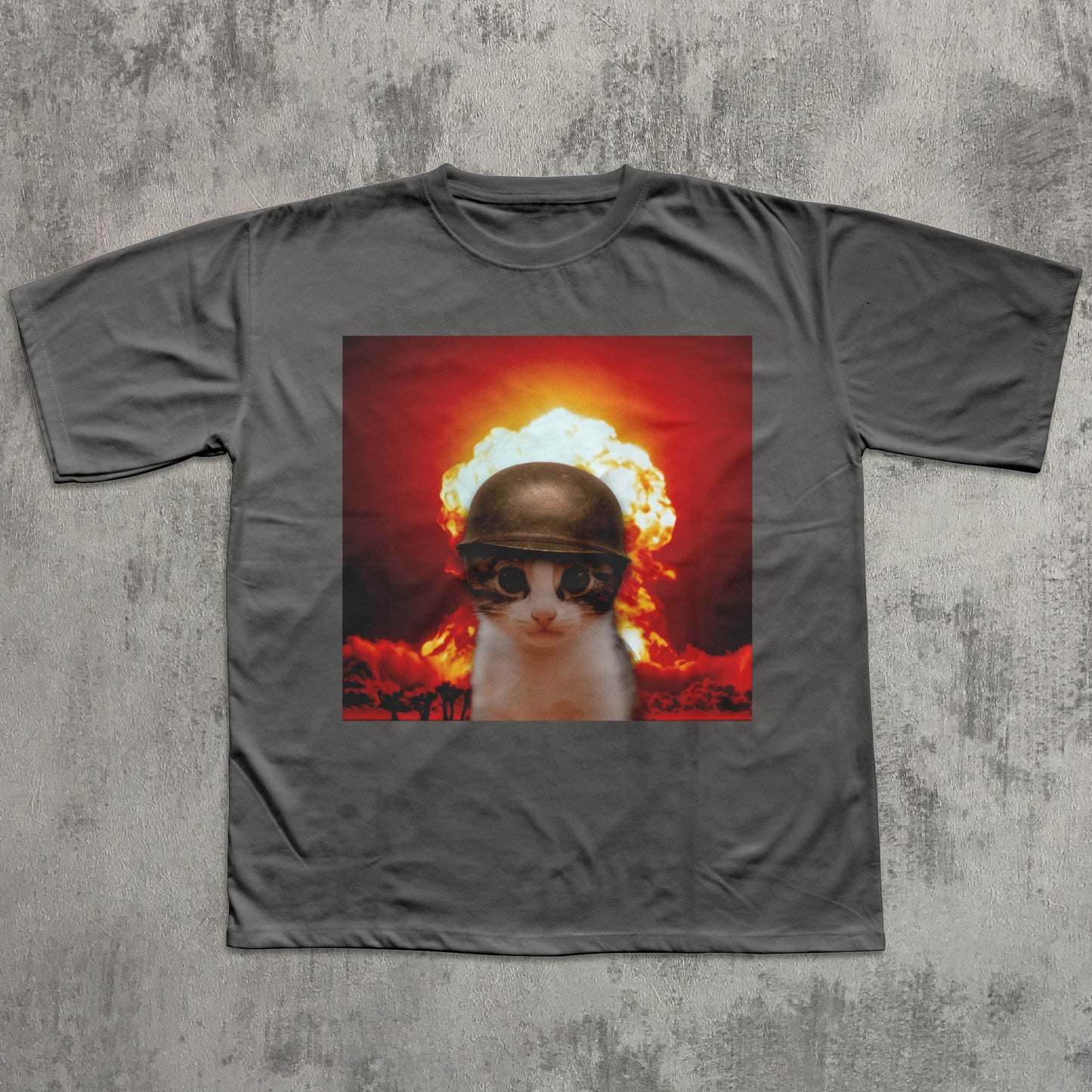 Gray t-shirt with a graphic of a cat wearing a helmet and goggles in front of an explosion on a concrete surface.