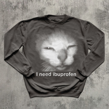 Gray graphic sweatshirt with retro halftone cat image and comedic quote ‘I need ibuprofen,’ trendy meme clothing.