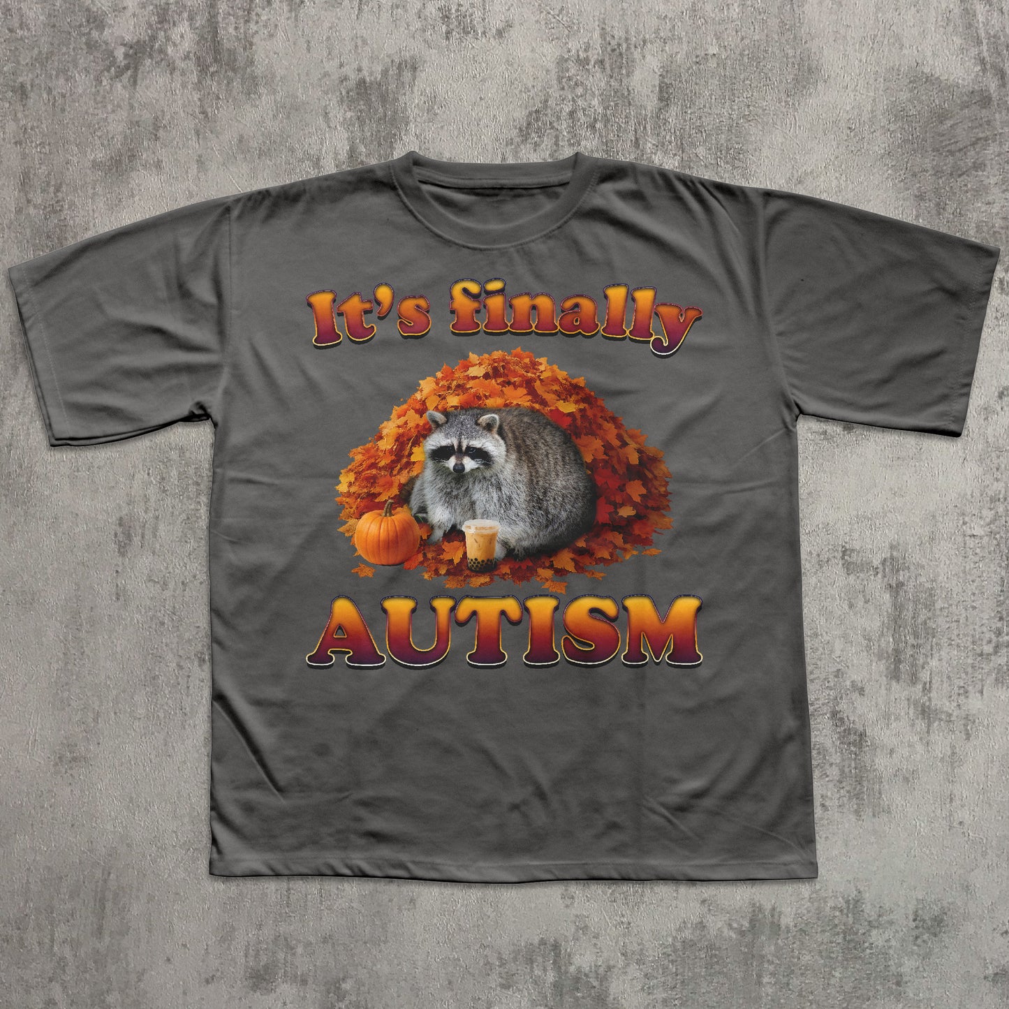 Gray t-shirt with a raccoon graphic and 'It's finally autism' text on a textured gray background