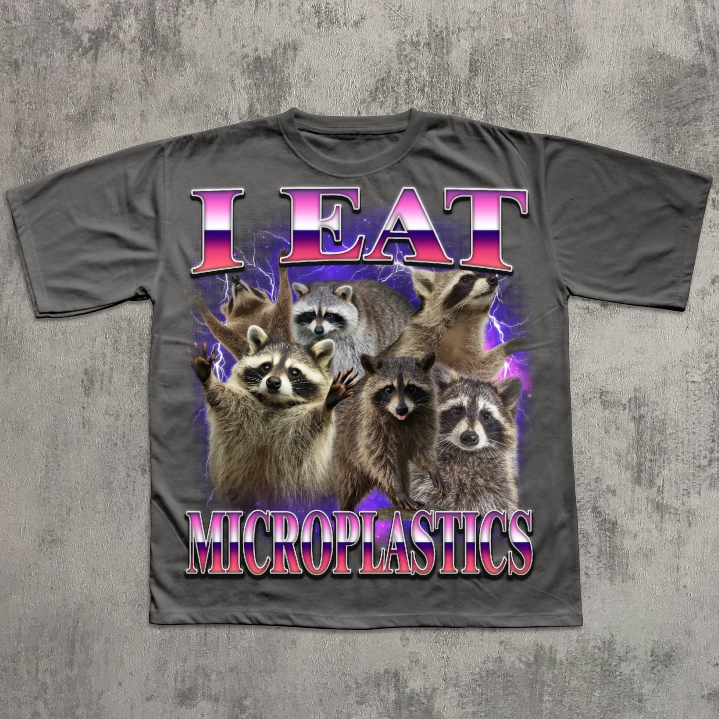 T-shirt with raccoons and 'I Eat Microplastics' text on a textured gray background