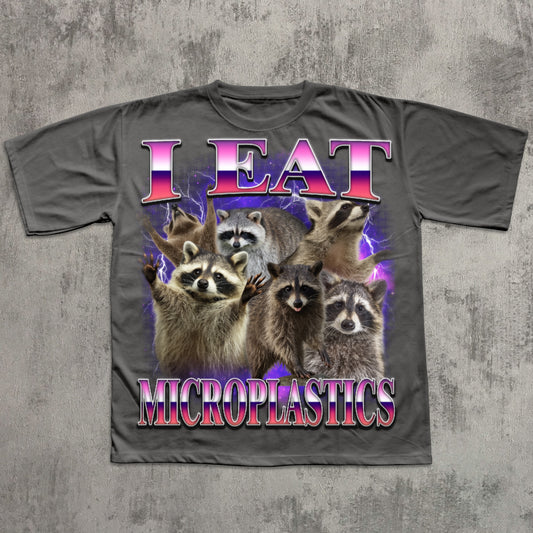 T-shirt with raccoons and 'I Eat Microplastics' text on a textured gray background