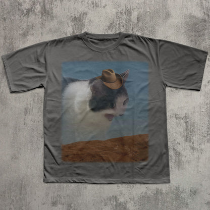 Gray t-shirt with a printed design of a cat wearing a cowboy hat on a textured gray background