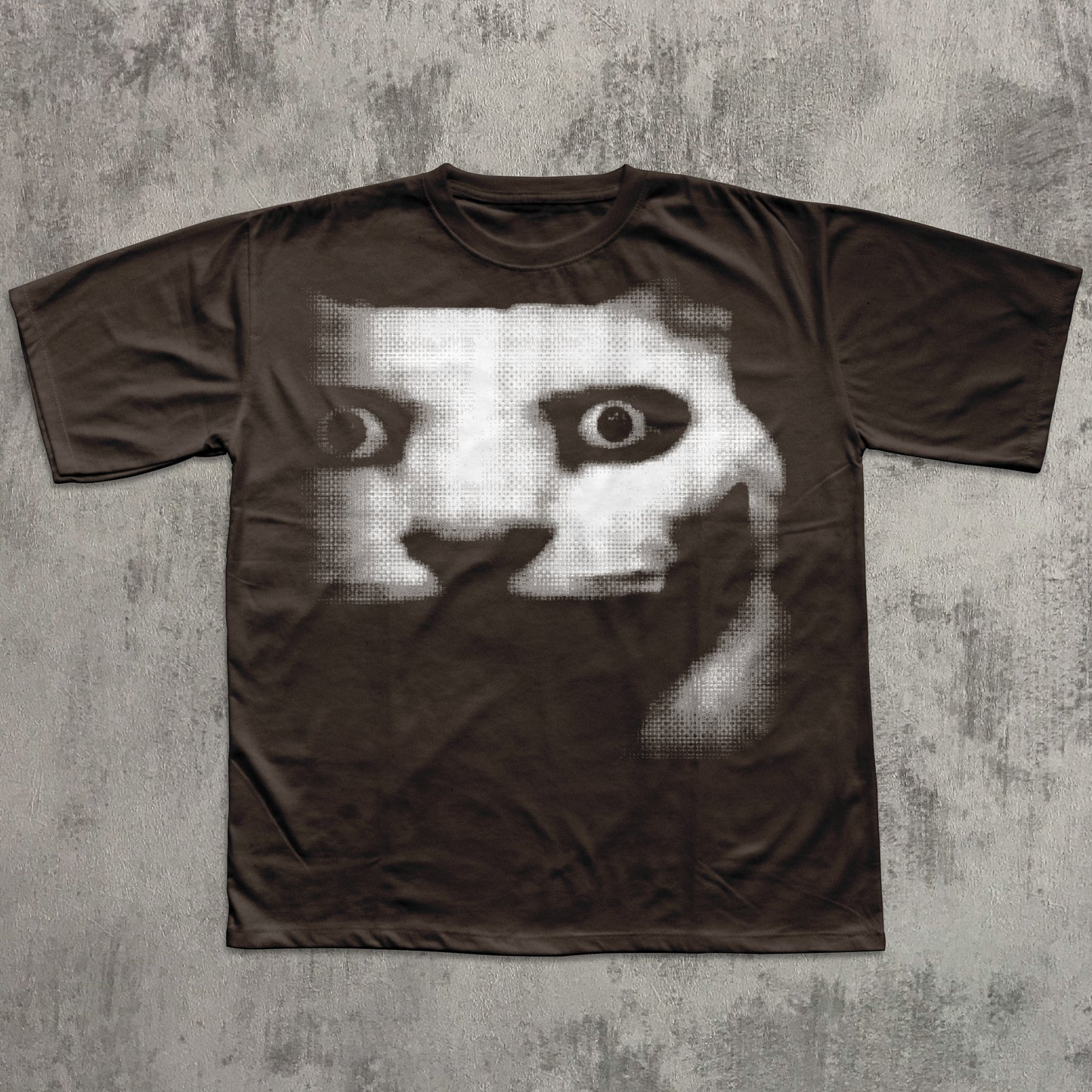 Brown t-shirt with a graphic design of a face with one eye on a textured gray background