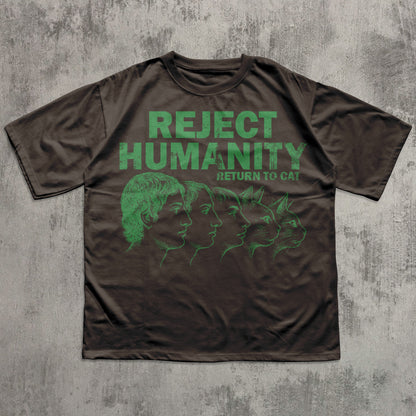 Brown t-shirt with green graphic and text 'REJECT HUMANITY RETURN TO CAT' on a textured gray background