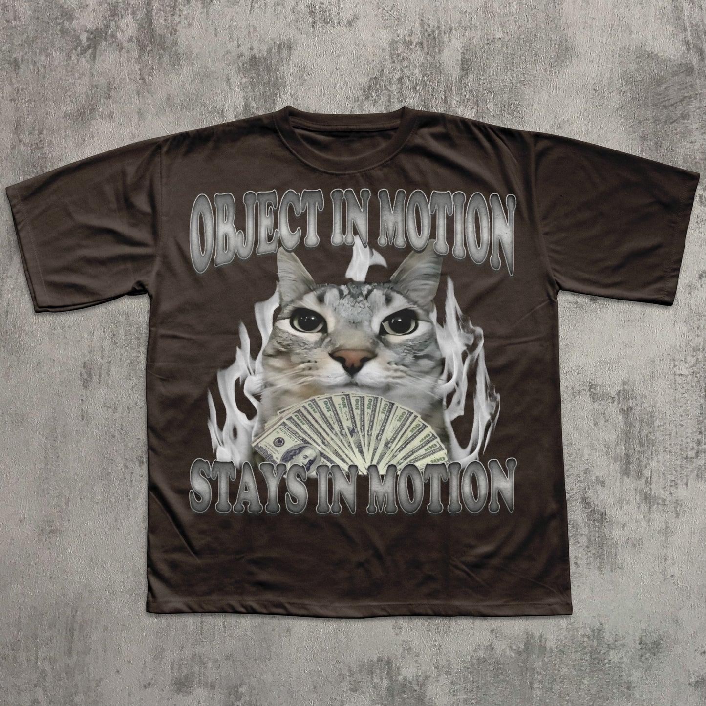 Brown t-shirt with a graphic of a cat, money, and flames on a textured gray background