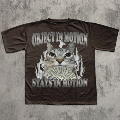 Brown t-shirt with a graphic of a cat, money, and flames on a textured gray background
