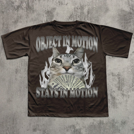 Brown t-shirt with a graphic of a cat, money, and flames on a textured gray background