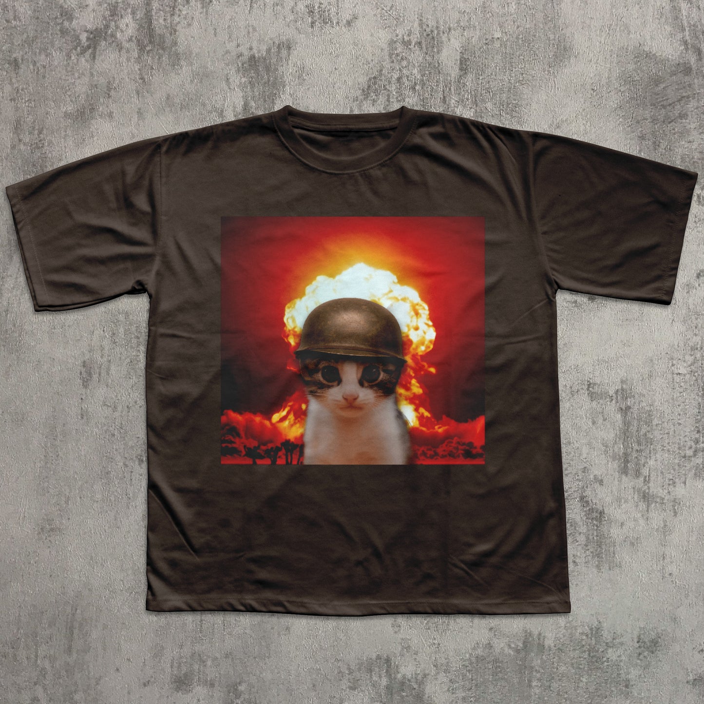 Brown t-shirt with a graphic of a cat wearing a helmet and goggles in front of an explosion on a concrete floor.