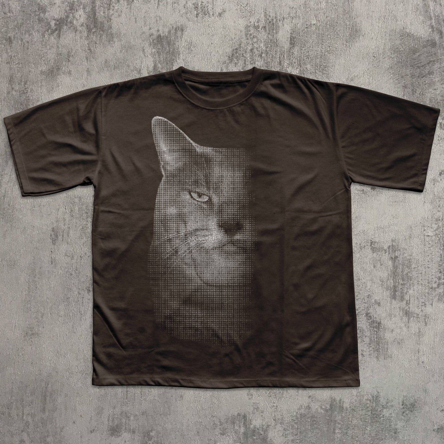 Brown t-shirt with a graphic of a cat's face on a textured gray background