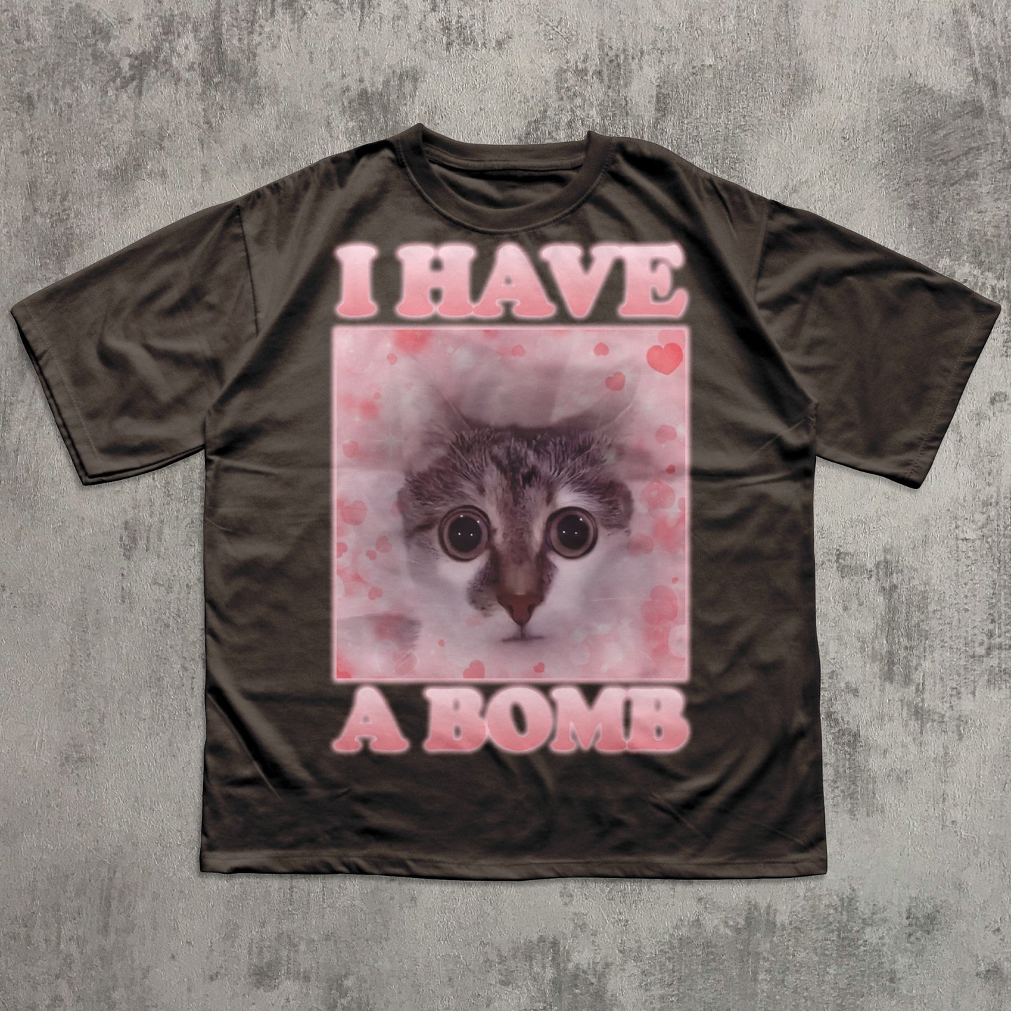 Brown t-shirt with a graphic of a cat and text 'I HAVE A BOMB' on a textured gray background