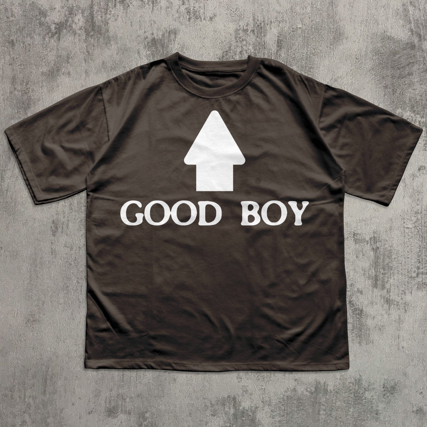 Brown t-shirt with 'GOOD BOY' text and white arrow graphic on a textured gray background