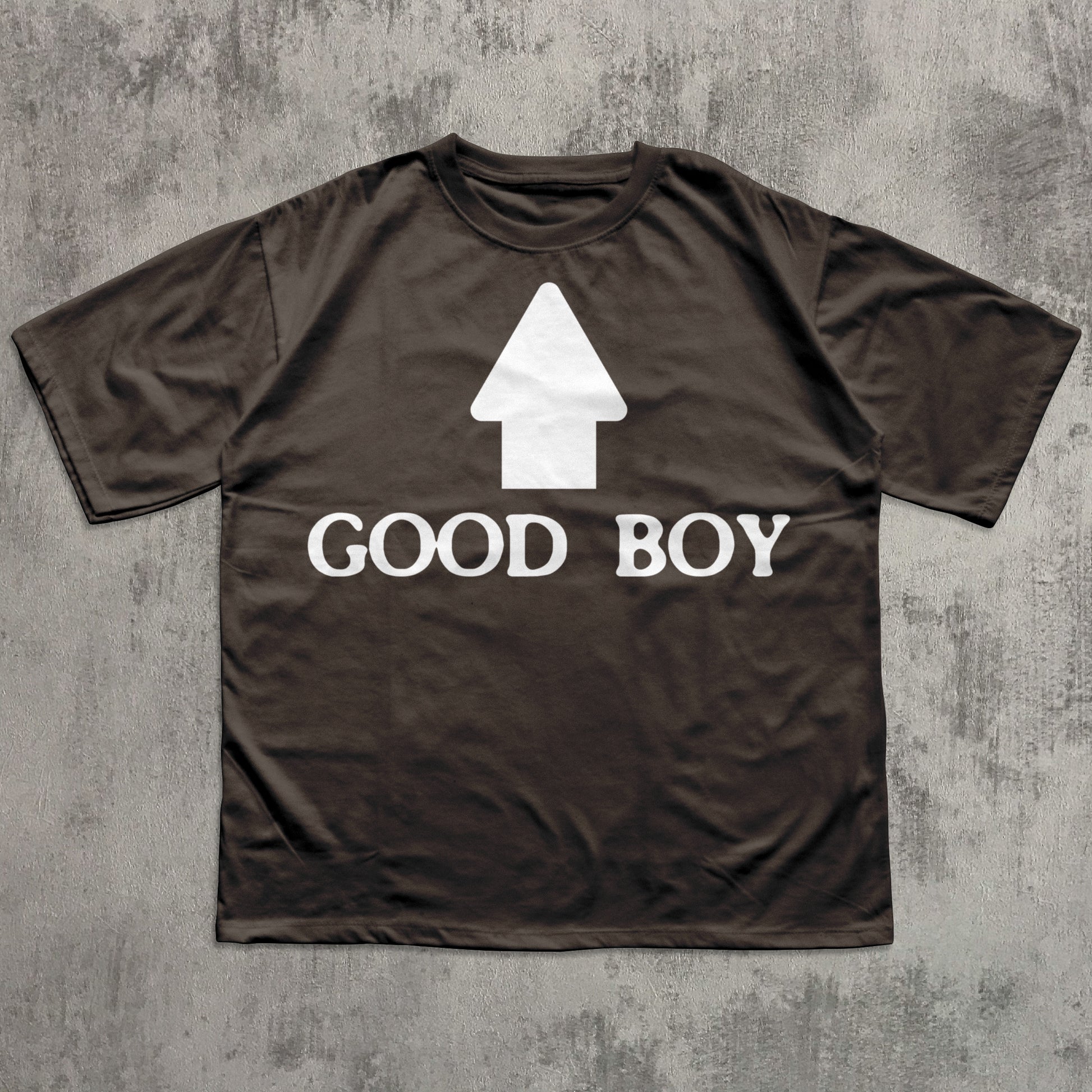 Brown t-shirt with 'GOOD BOY' text and white arrow graphic on a textured gray background