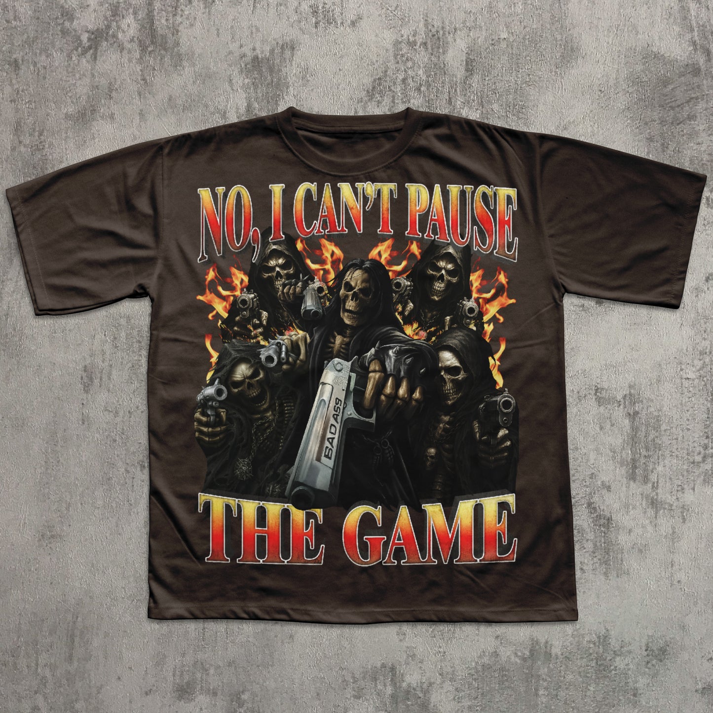 T-shirt with graphic design of skeletons holding guns and text 'No, I Can't Pause The Game' on a concrete background