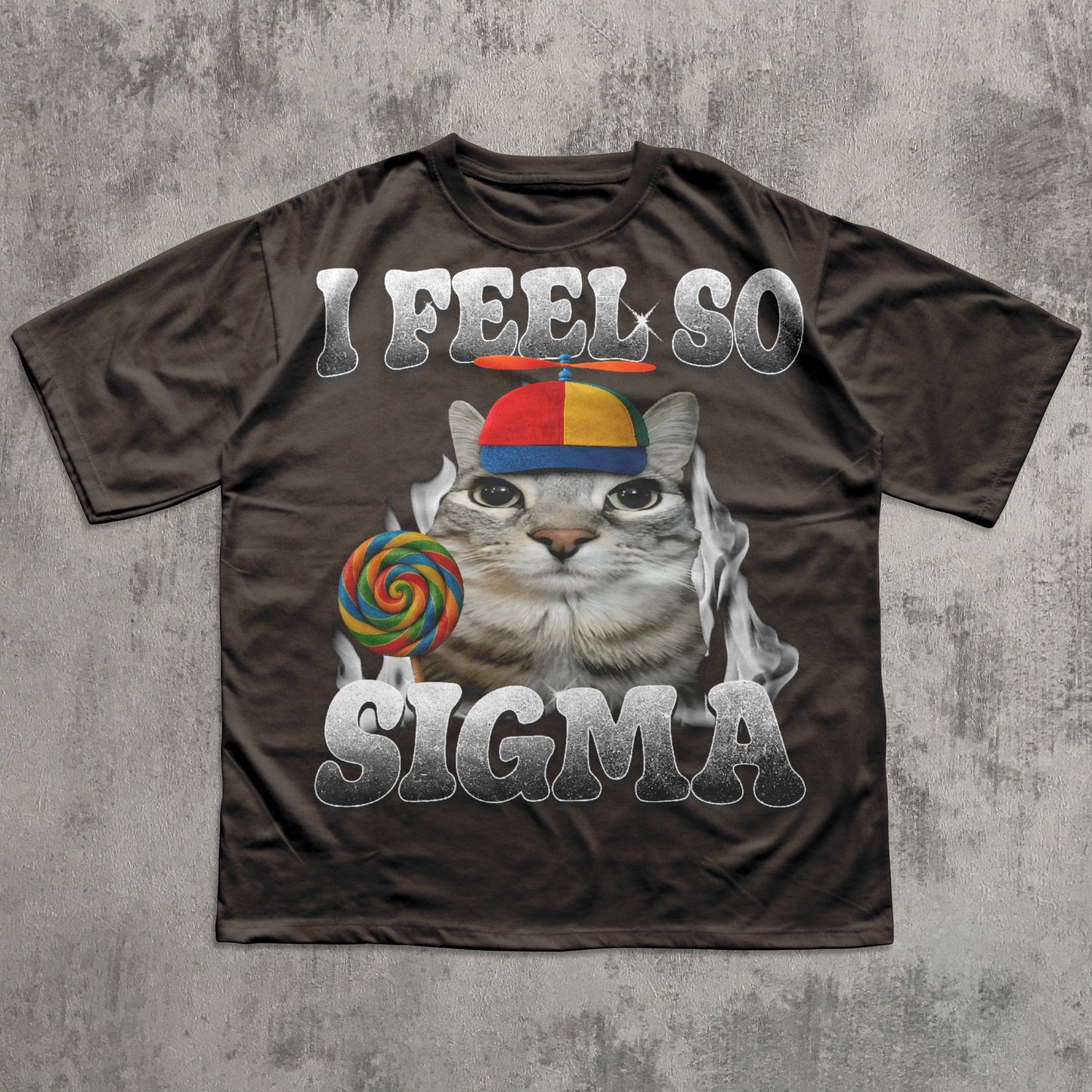 Brown t-shirt with a graphic of a cat  and lollipop meme, text 'I FEEL SO SIGMA' on a concrete surface.