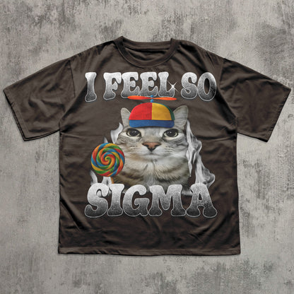 Brown t-shirt with a graphic of a cat  and lollipop meme, text 'I FEEL SO SIGMA' on a concrete surface.