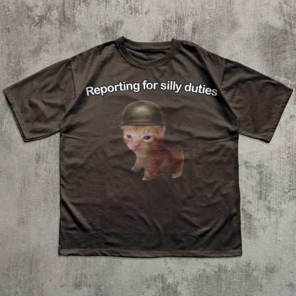 Brown t-shirt with a kitten wearing a helmet and text 'Reporting for silly duties' on a textured gray background