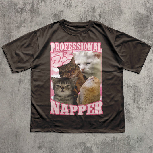 funny Brown t-shirt with a graphic of cats and the text 'Professional Napper' on a concrete surface.