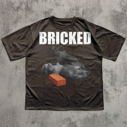 Brown t-shirt with 'BRICKED' text and graphic of a Cat and brick on a textured gray background