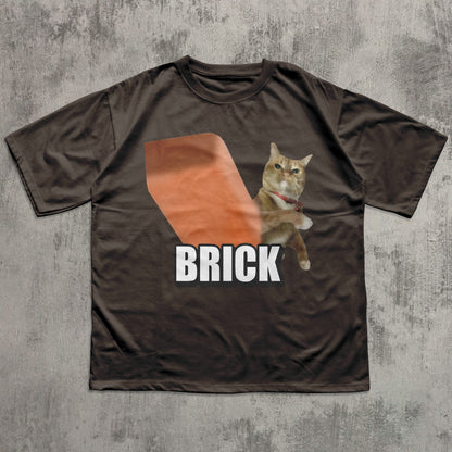 Brown t-shirt with a cat graphic and 'BRICK' text on a textured gray background