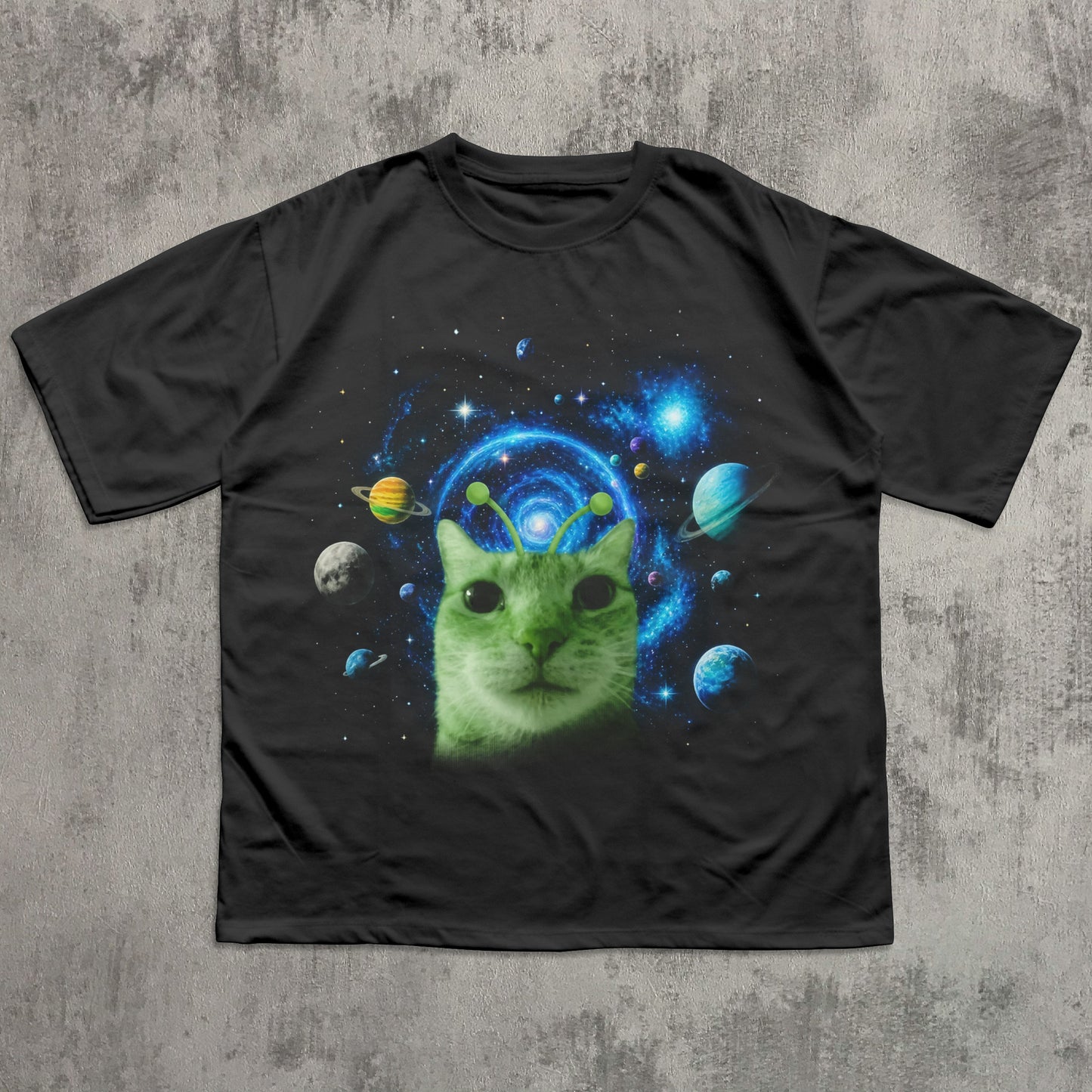 Black t-shirt with a green cat in space design on a concrete surface