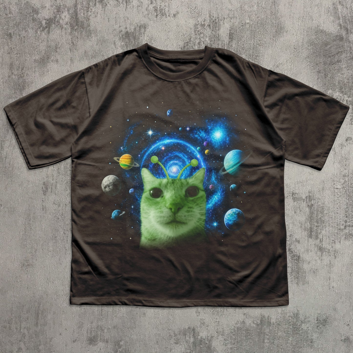 Brown t-shirt with a green cat in space design on a textured gray background