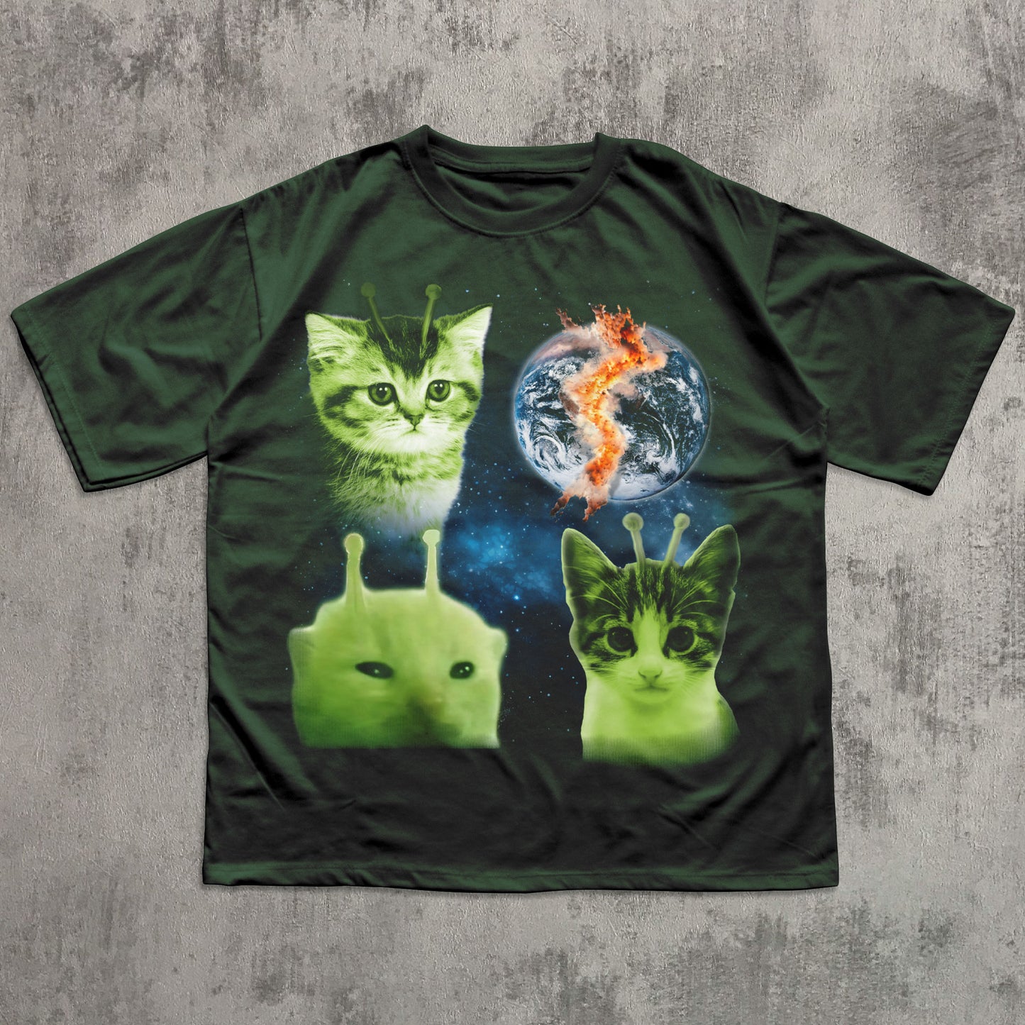Green t-shirt with alien and cat design on a textured gray background